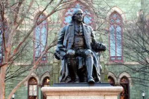 A statue of ben franklin sitting on top of a pedestal.
