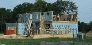 A group of people building a house on top of grass.