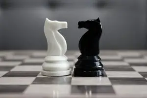 Two chess pieces are facing each other on a chessboard.