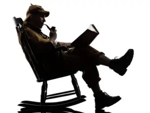 A man sitting in a rocking chair with a book.