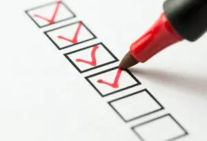A red pen is marking the checkboxes on a checklist.