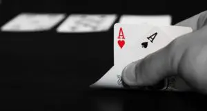A person holding two aces on top of cards.