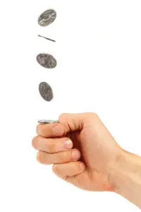 A hand holding a coin and three coins flying in the air.