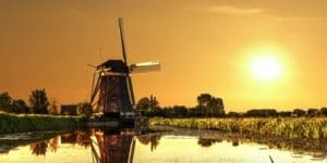 A windmill is in the water near some trees.