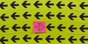 A pink post it note with an arrow on it