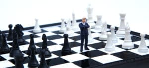 A small figure of a man standing on top of a chess board.