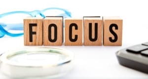 Focus spelled out in wooden blocks with a magnifying glass.