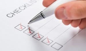 A person is writing on the checklist of their tasks.